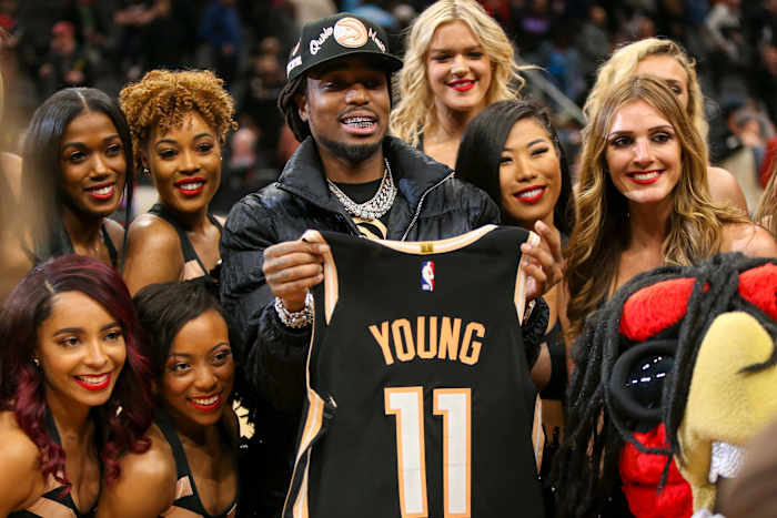 Rapper Quavo celebrates with cheerleaders while holding the jersey of Atlanta Hawks guard Trae Young (not pictured) after a victory against the Miami Heat at State Farm Arena.